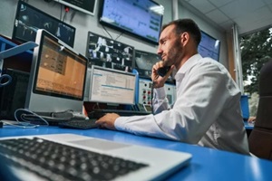 man working on computer while talking on phone