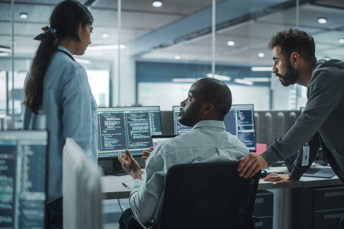 Diverse Group of Energetic Professionals Team Meeting in Modern Office: Brainstorming IT Programmers Use Computer, Talk Strategy, Discuss Analysis. Innovative Software Engineers Develop App Program