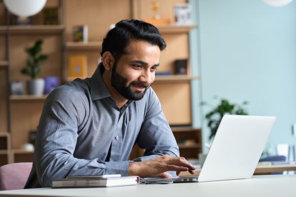 Man Smiling At Laptop Pleased With His Identity & Access Management Solutions