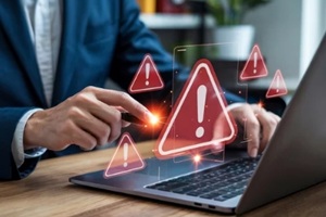 man in suit interacting with laptop displaying multiple warning signs on a wooden surface area desk