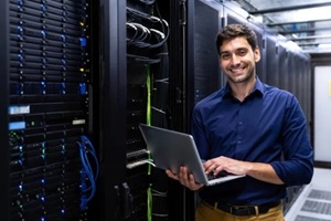 smiling IT professional managing servers in a data center environment