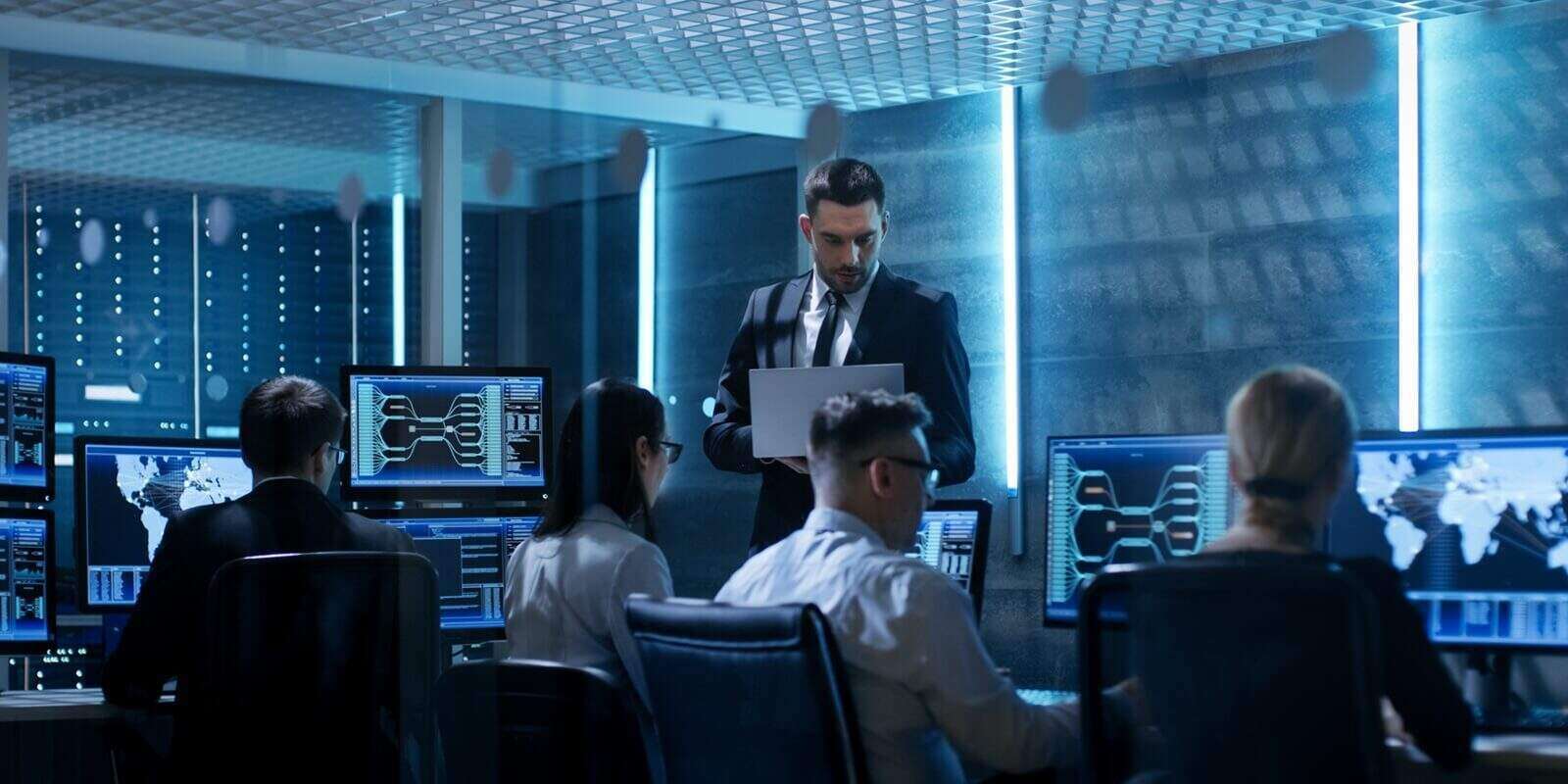 professional it engineers working in system control center full of monitors and servers