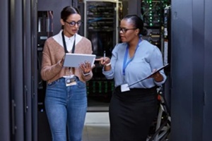Woman with tablet in server room representing infrastructure services.