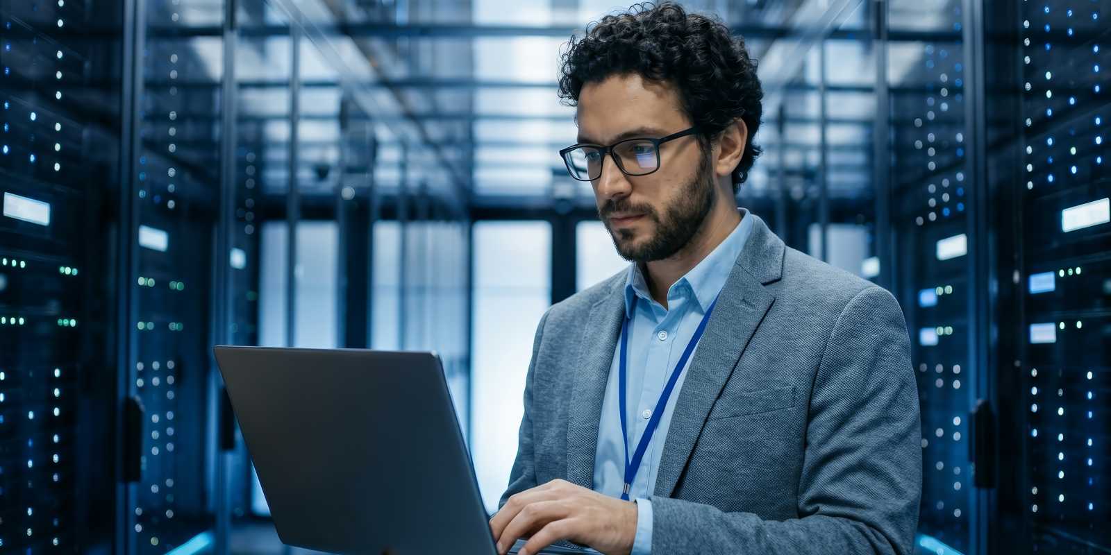 Senior IT professional in a data center working on a laptop among server racks providing managed IT services and infrastructure support