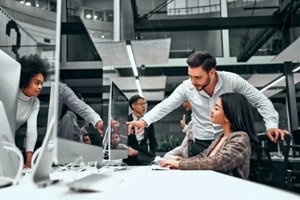 formally dressed man shows a young woman's work on a computer screen
