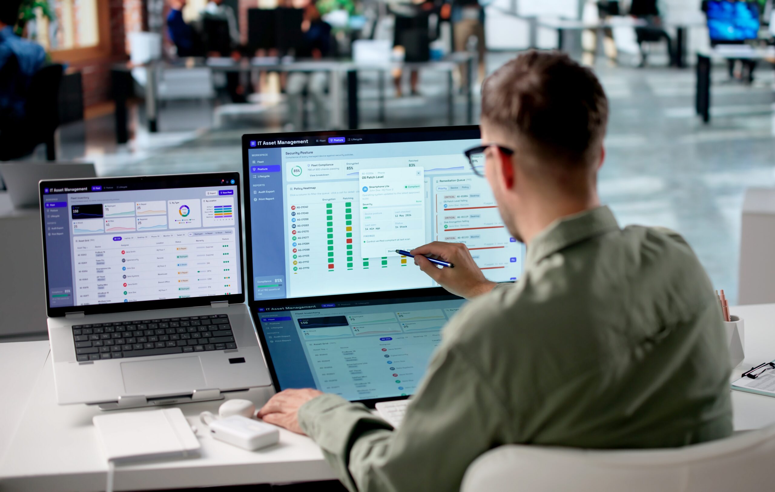 IT consultant reviewing asset management dashboard with security ratings on dual screen