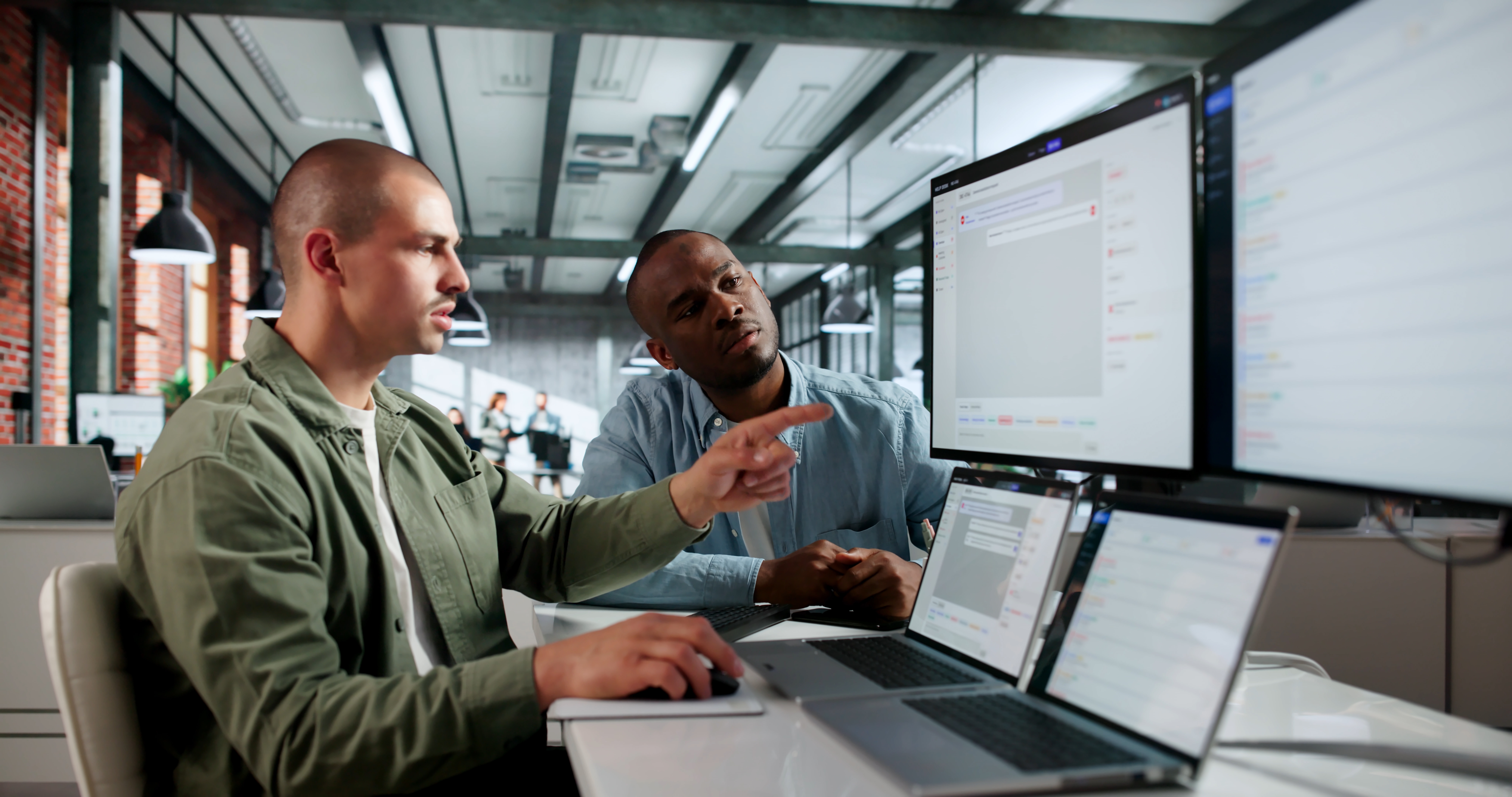 IT consultants collaborating and reviewing project details on laptops and a large display screen