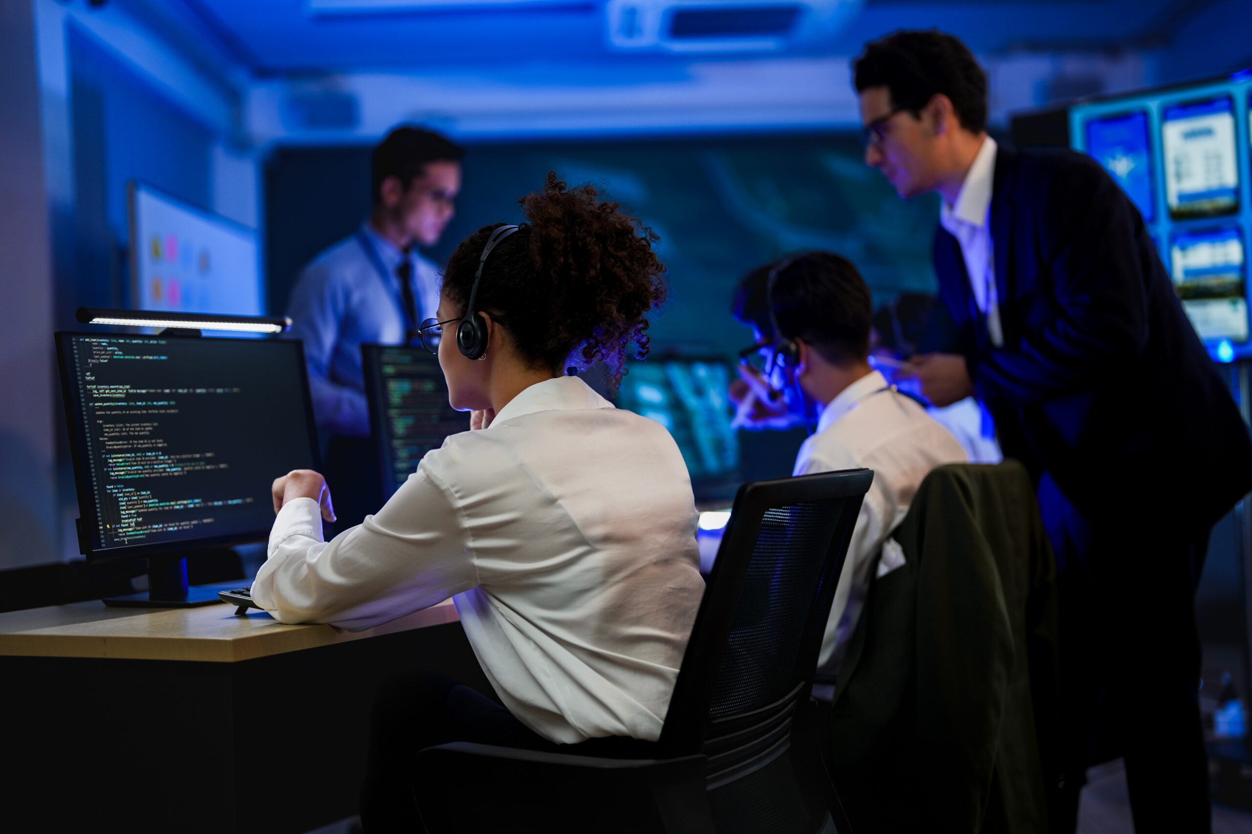 IT support team wearing headsets working at monitors in a busy technical operations center