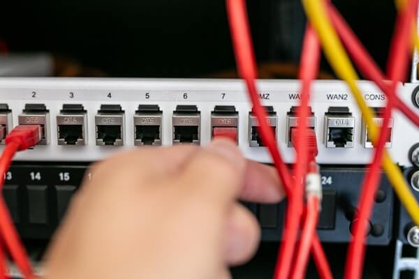 close-up of a person's hand plugging an Ethernet patch cable