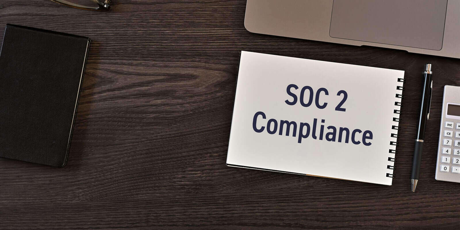 secure technology and SOC 2 Compliance on notebook with laptop, calculator, glasses